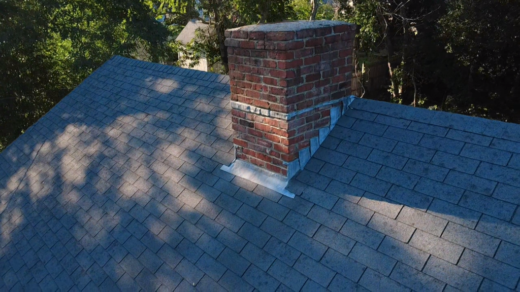 Brick chimney with new flashing at the roof line after repair
