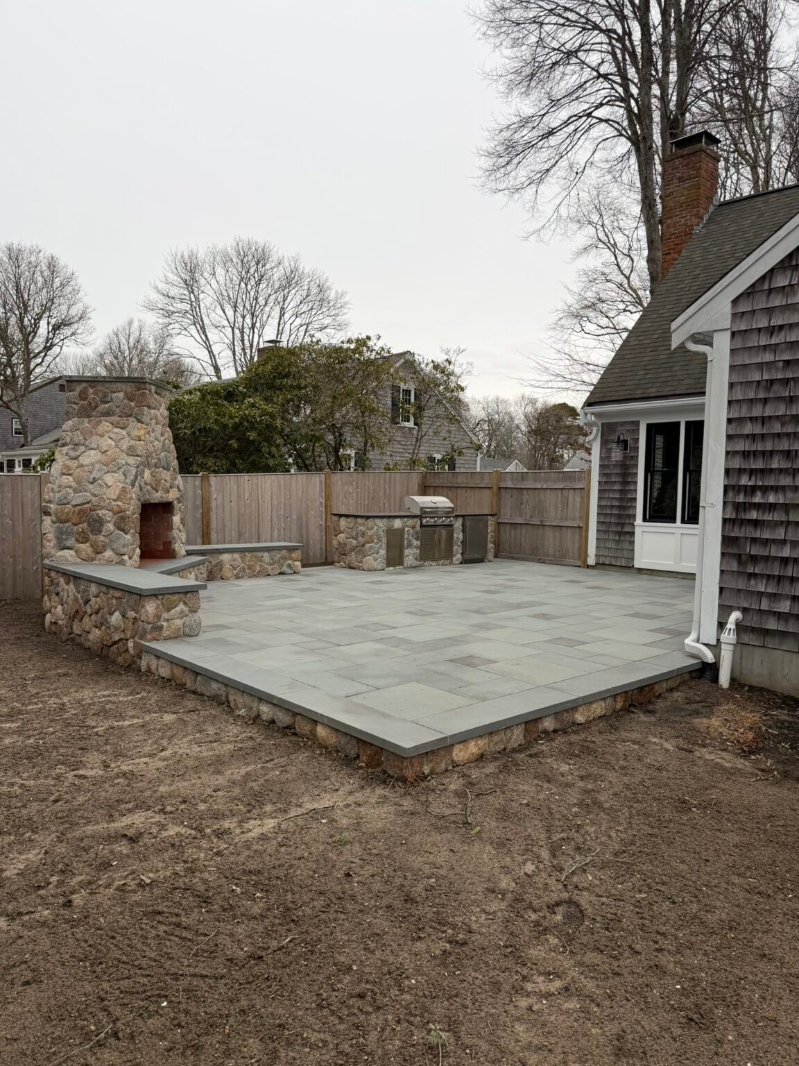 Outdoor fireplace and bluestone patio built by Bridi Masonry in Cape Cod, MA