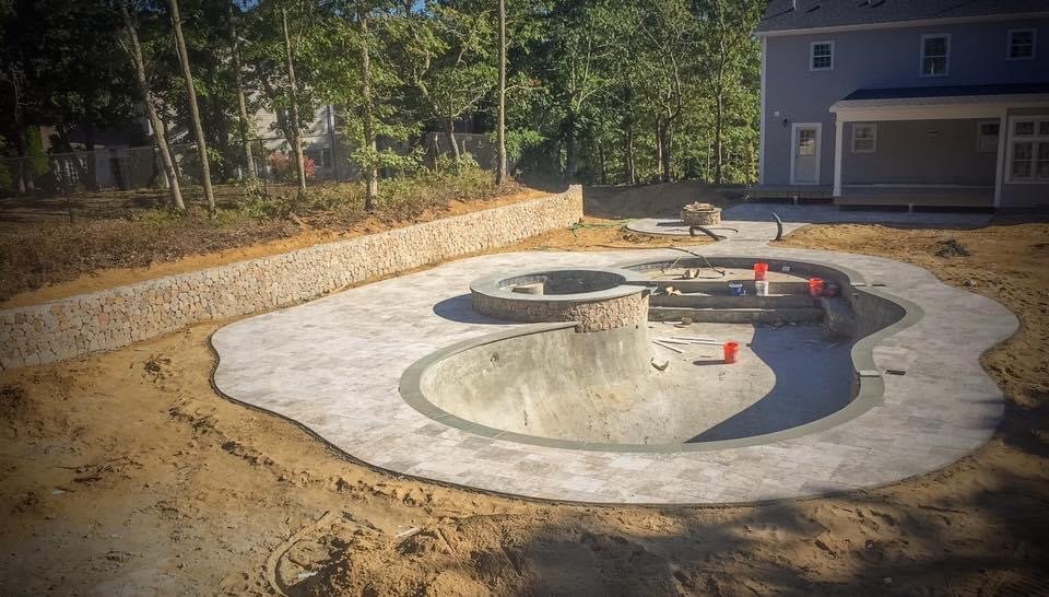 Pool deck and fire pit under construction built by Bridi Masonry in Cape Cod, MA