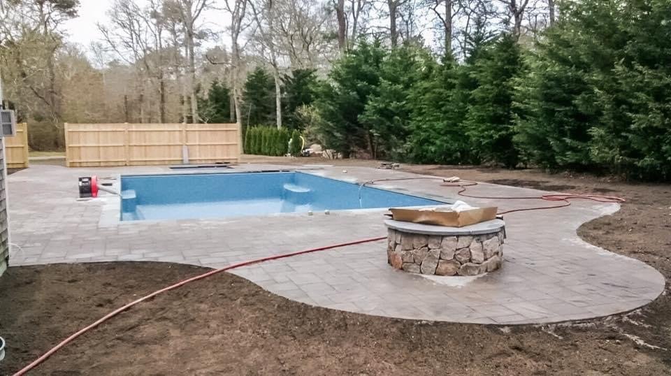 Pool deck with stone fire pit built by Bridi Masonry in Cape Cod, MA