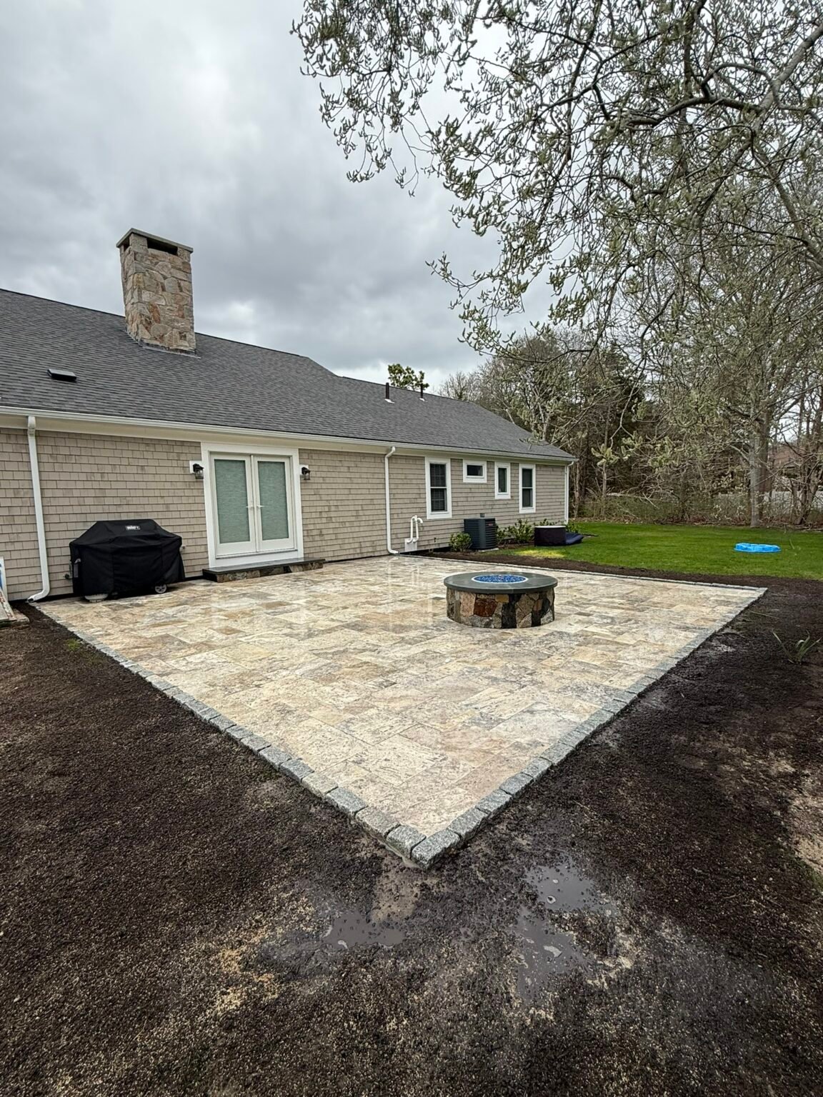 Travertine patio with fire pit built by Bridi Masonry in Cape Cod, MA
