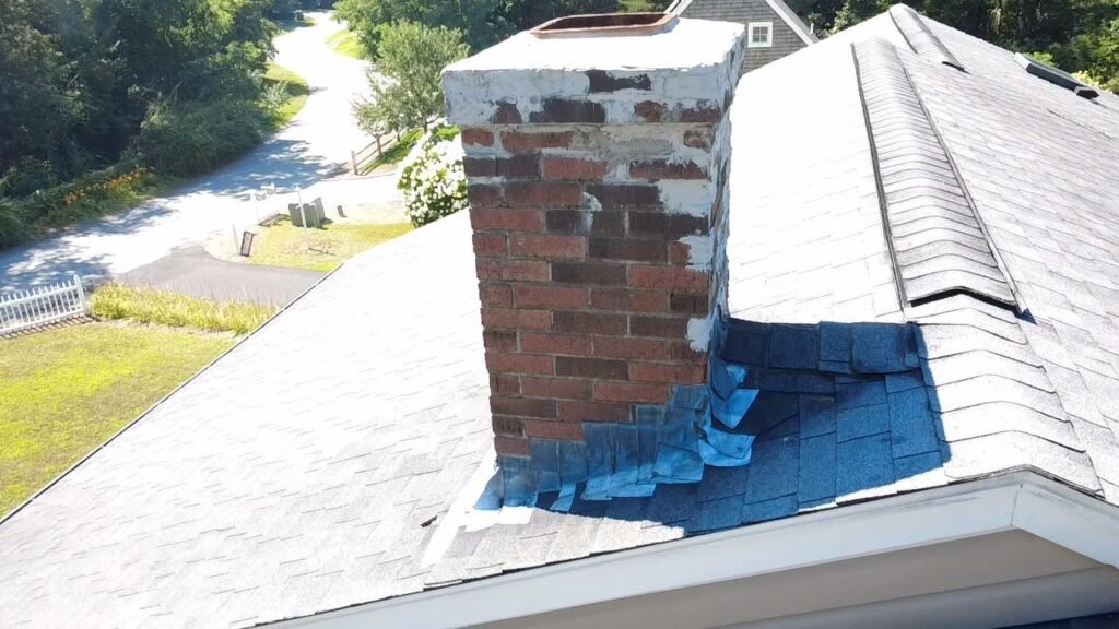 Chimney flashing replacement in progress with shingles lifted around the base