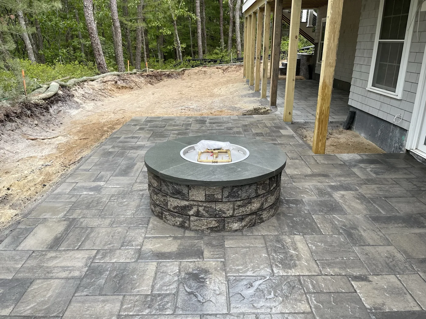 Round stone fire pit set into a paver patio, Cape Cod MA