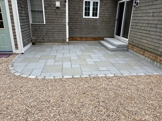 New paver patio with cobblestone border and granite front steps in Mashpee, MA